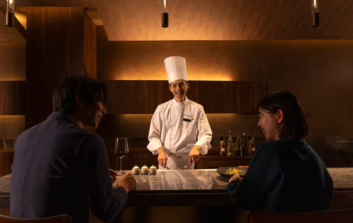 A man and a woman enjoying teppanyaki with a chef.