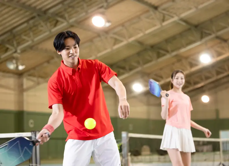 Two people, a man and a woman, hitting the ball back and forth on a pickleball court.