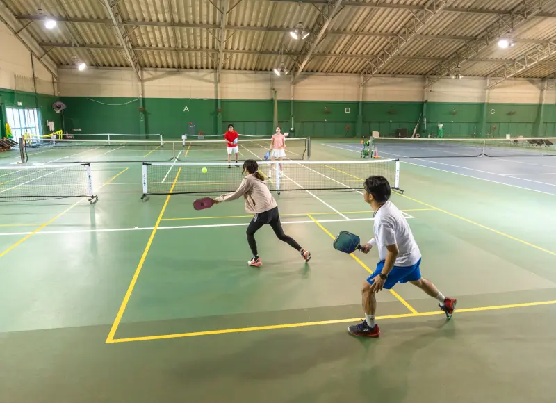 Four people playing pickleball on an indoor court.